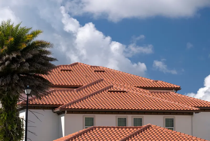 House with red tile roof and clouds.
